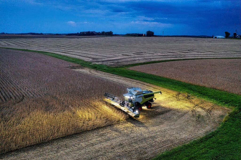 Drone captures a combine harvester working in Minnesota soybean fields at dusk.